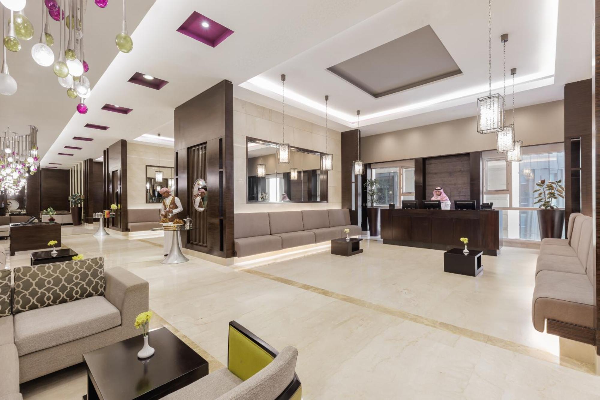 Swissotel Makkah La Meca Exterior foto The photo shows a modern hotel lobby. It features a spacious area with a combination of light and dark-colored decor. There are comfortable seating arrangements with sofas and lounge chairs. The walls have a sleek design, with some decorative element