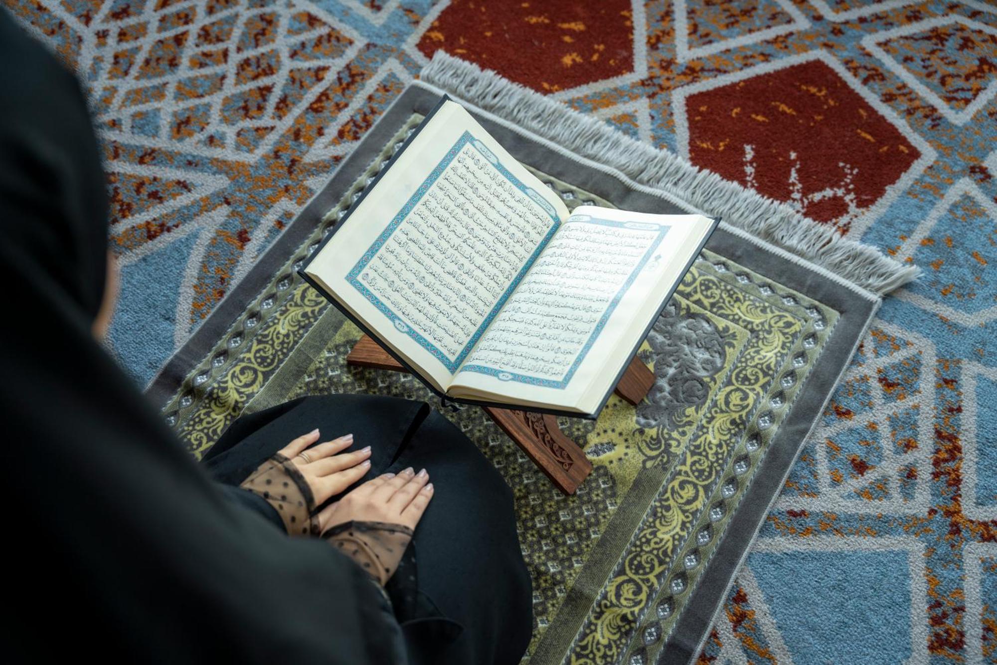 Swissotel Makkah La Meca Exterior foto The photo shows an individual, likely sitting on a prayer mat, with their hands placed on or near an open Quran. The Quran is displayed on a wooden stand, and the prayer mat features intricate patterns. The setting suggests a moment of prayer or refl