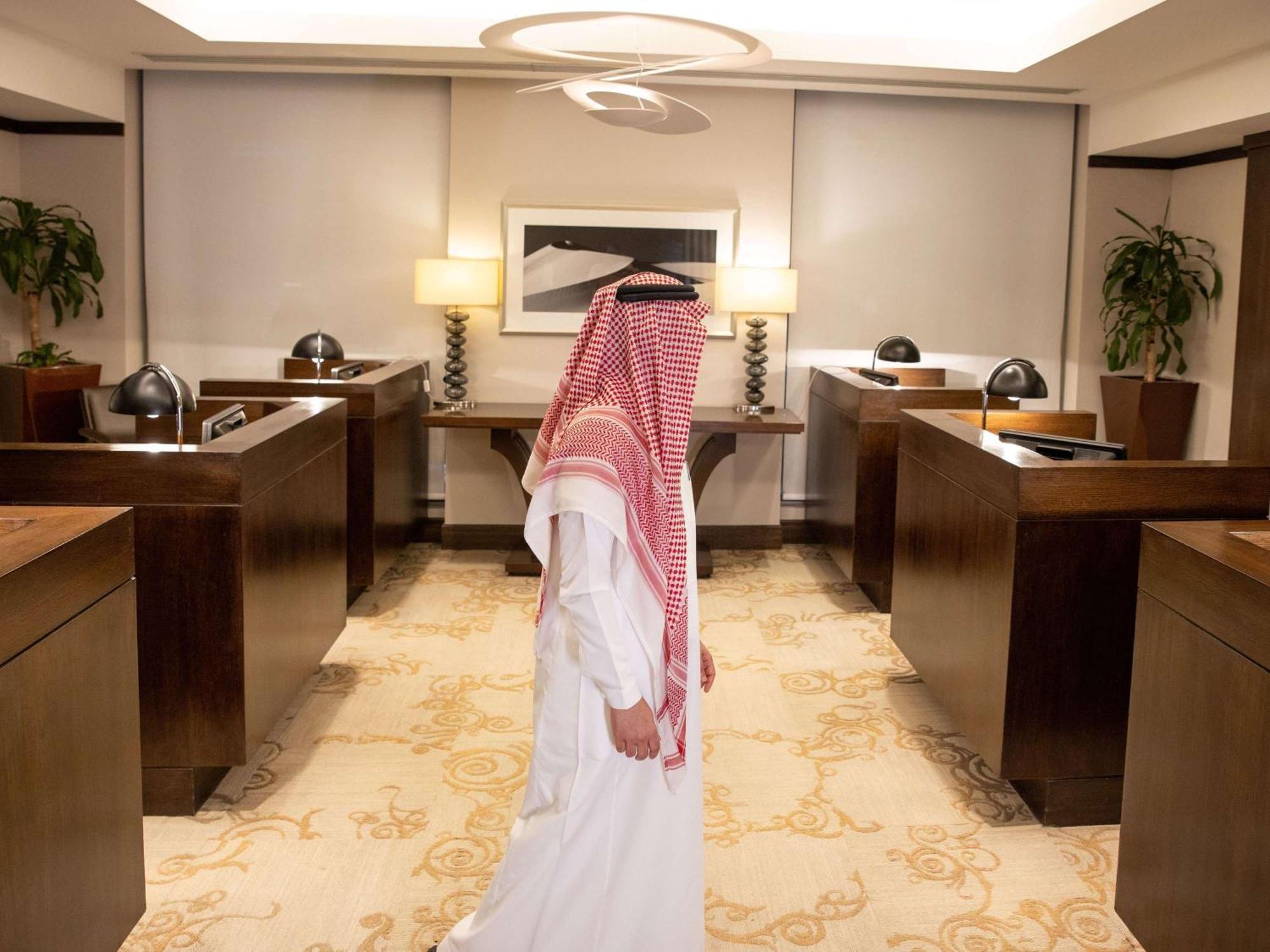 Swissotel Makkah La Meca Exterior foto The photo shows a man dressed in traditional attire, including a white thobe and a red-and-white checkered headscarf, walking through a modern office space. The office features wooden furniture, including desks and decorative lamps, creating a profes